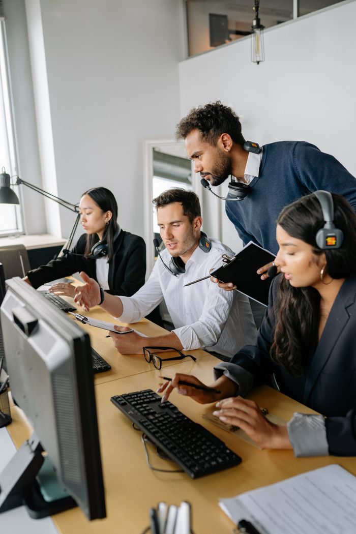 Crafting Captivating Headlines: Your awesome post title goes here A diverse group of call center employees working and collaborating at desks with headsets in a modern office.